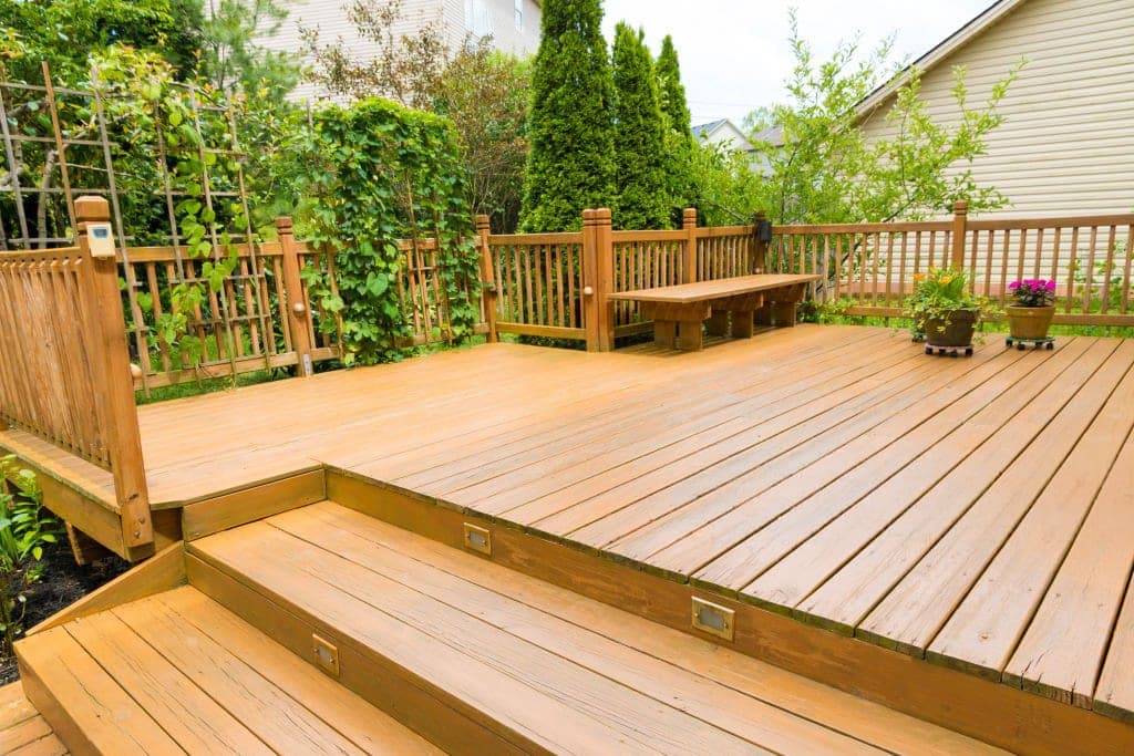 Multi-level wood deck with built-in bench, recessed step lights, and landscaped garden