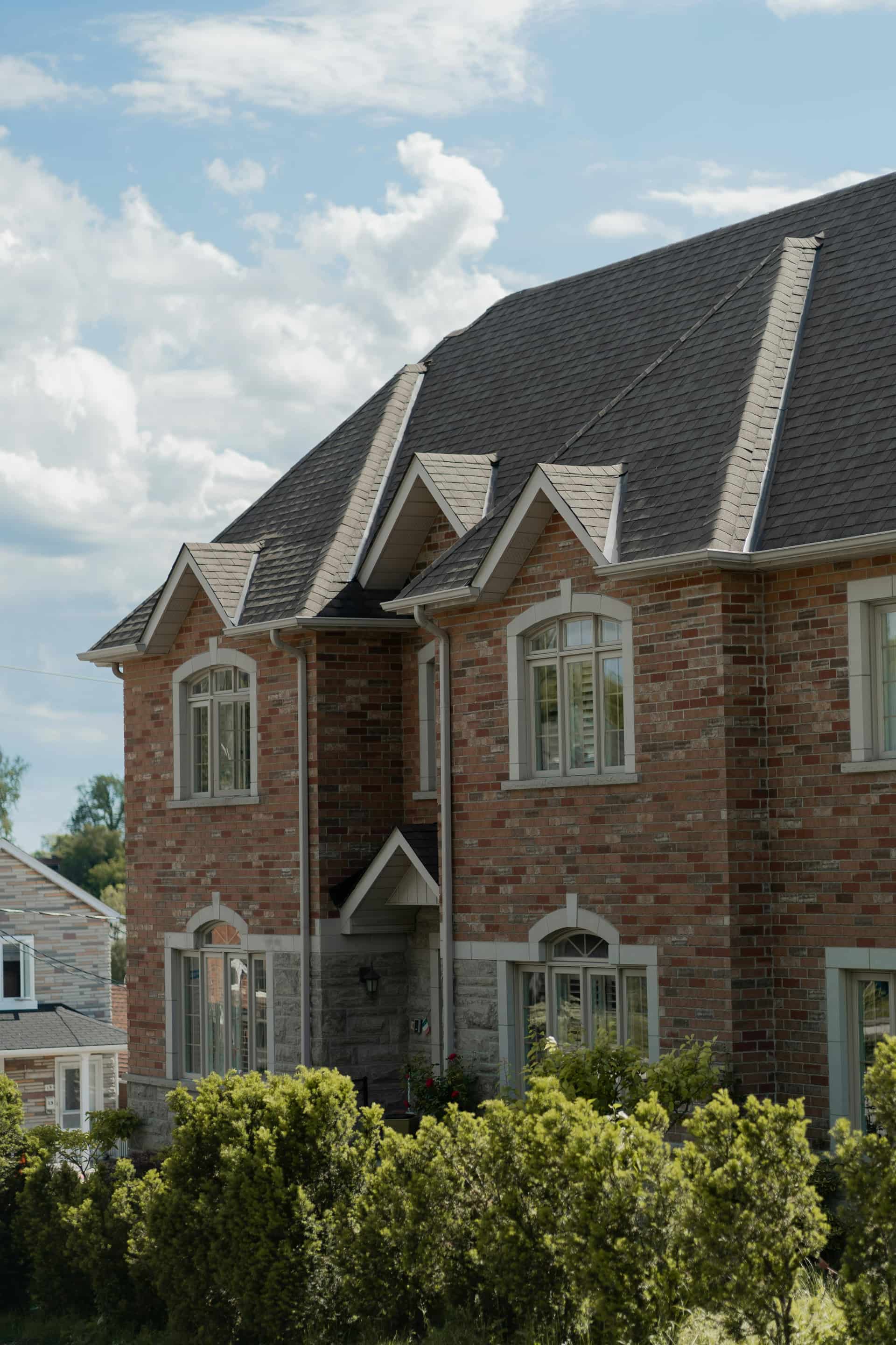 Brick Victorian-style home with multiple gables and dark architectural shingle roof