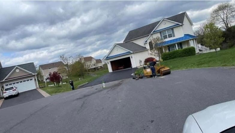 A roller compacting fresh asphalt on a driveway