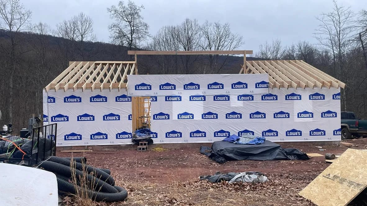 New home under construction with weather barrier and exposed roof trusses
