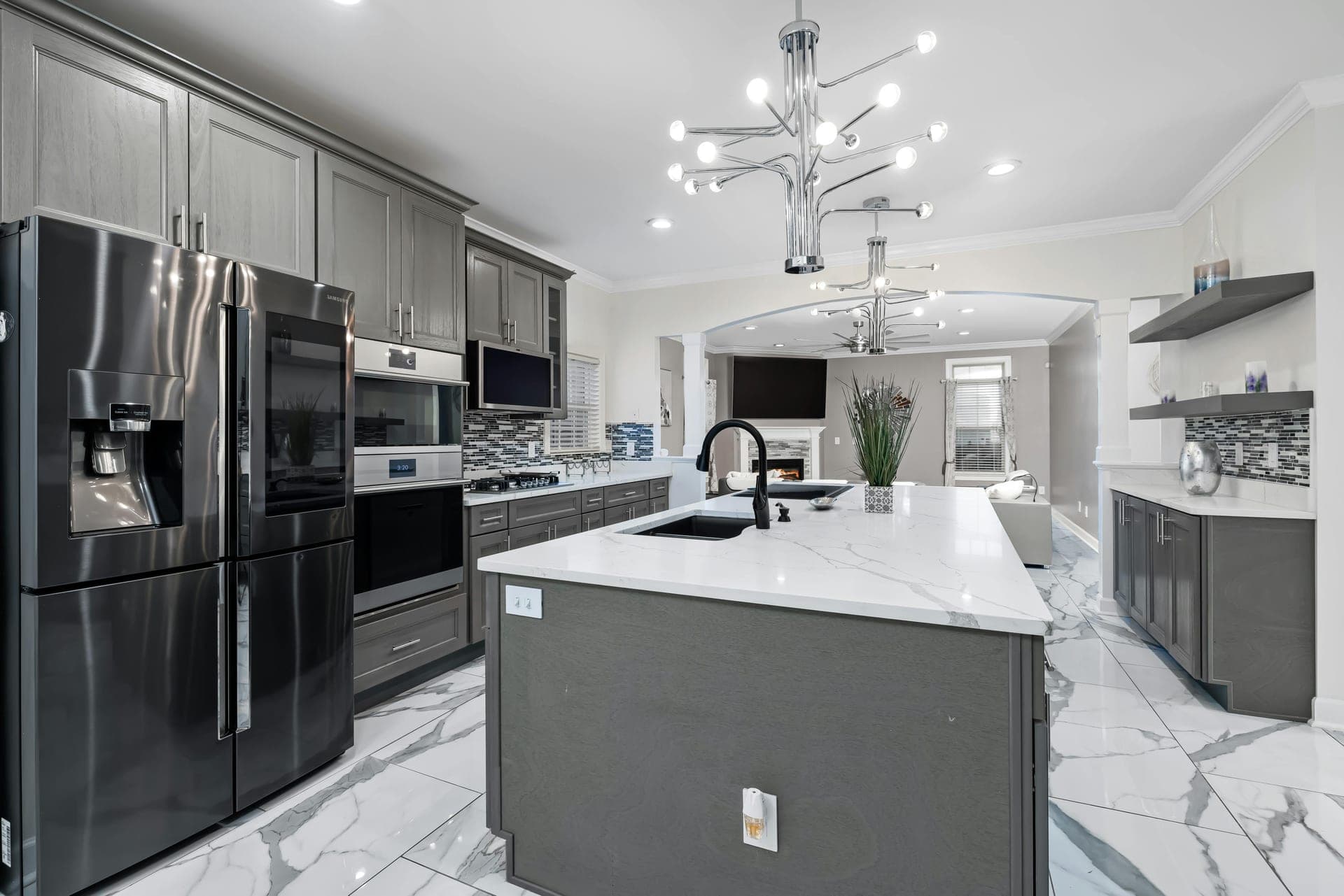 Modern gray kitchen with marble waterfall island and chrome chandelier