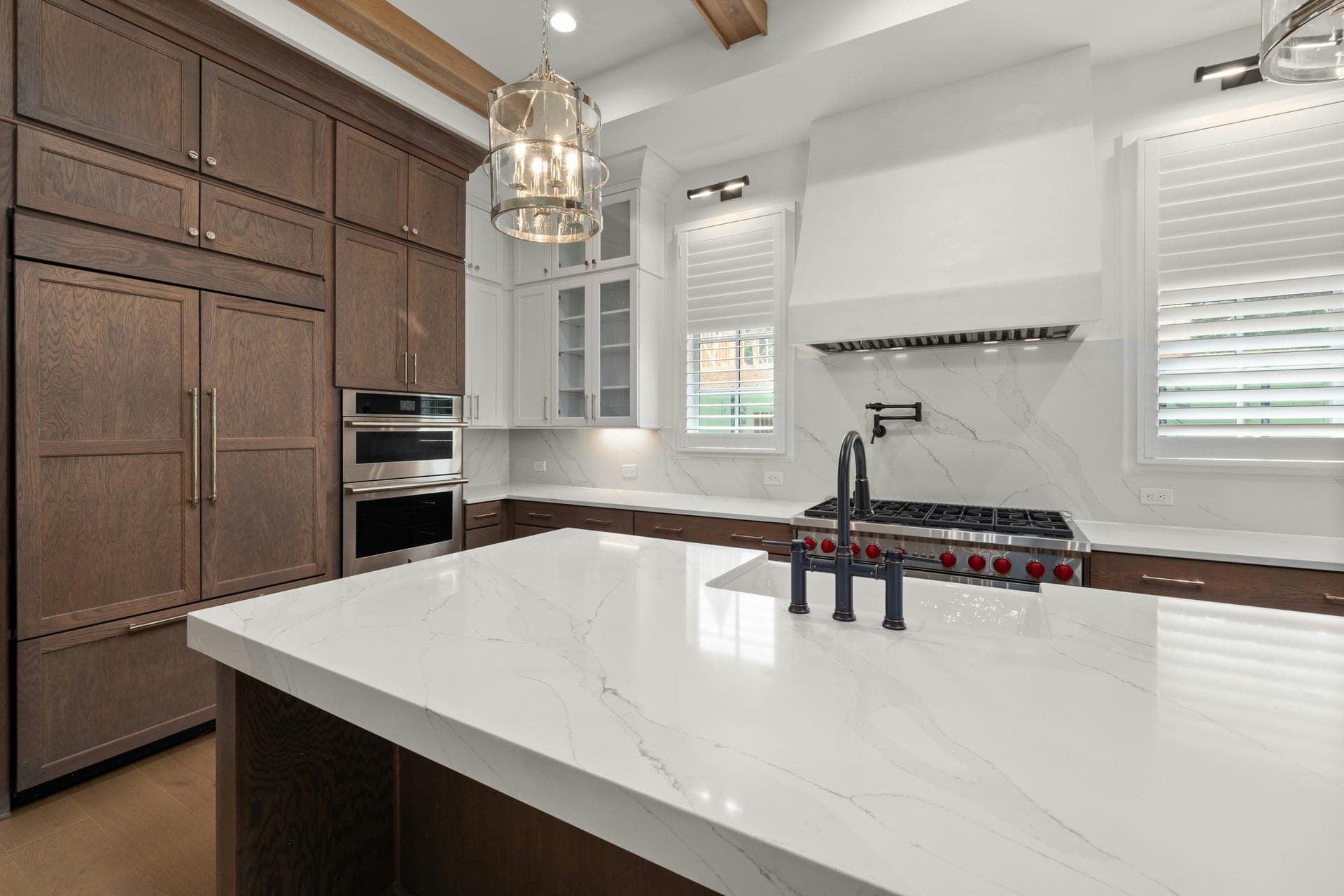 Two-tone kitchen with dark cabinetry, warm wood uppers, and black range hood