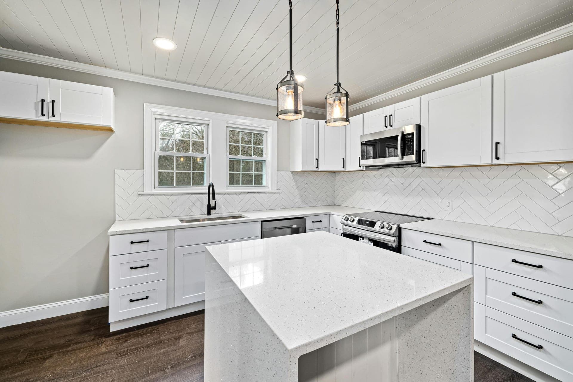 White kitchen with herringbone tile backsplash and shiplap ceiling