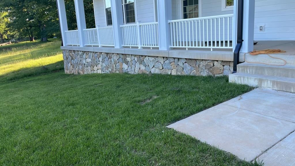 Finished stone veneer porch facade with white railings and walkway