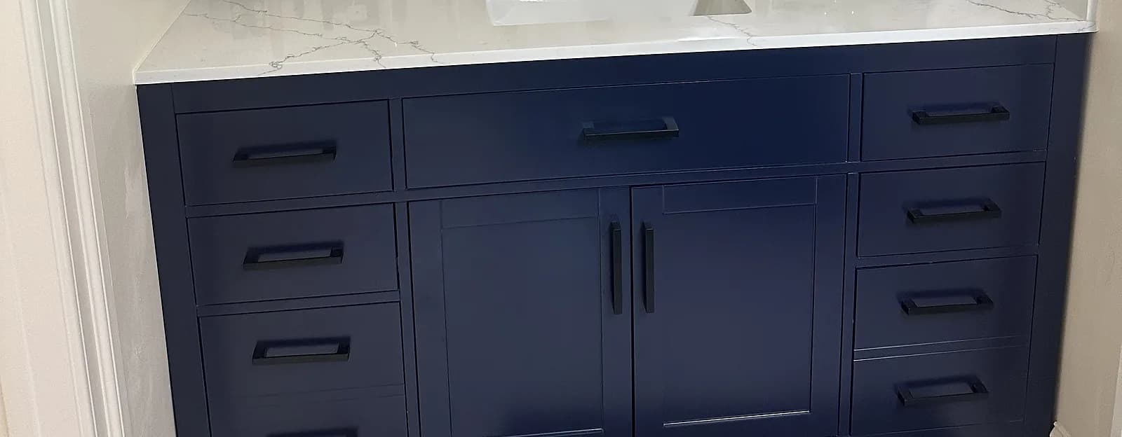 Navy shaker vanity with matte black pulls and a quartz top