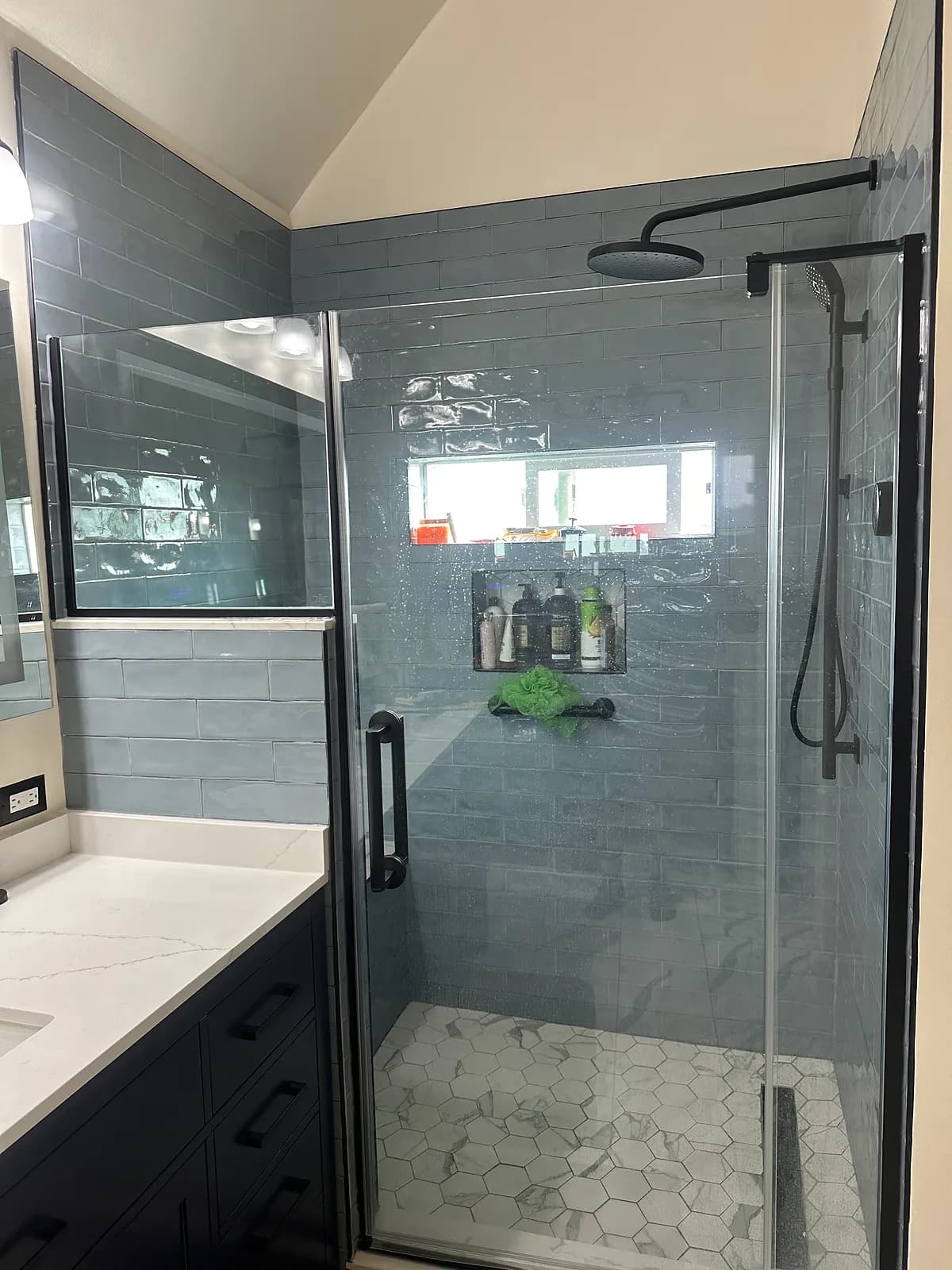 Primary bath with walk-in tile shower beside a quartz-topped navy vanity