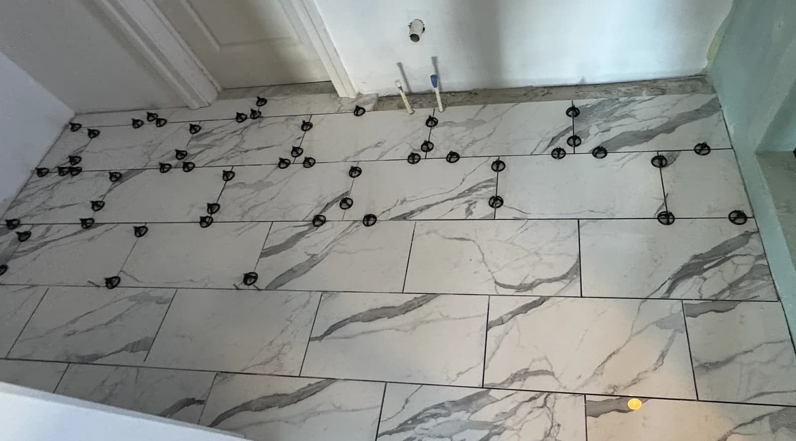 Large-format marble-look floor tile set with a tile leveling system