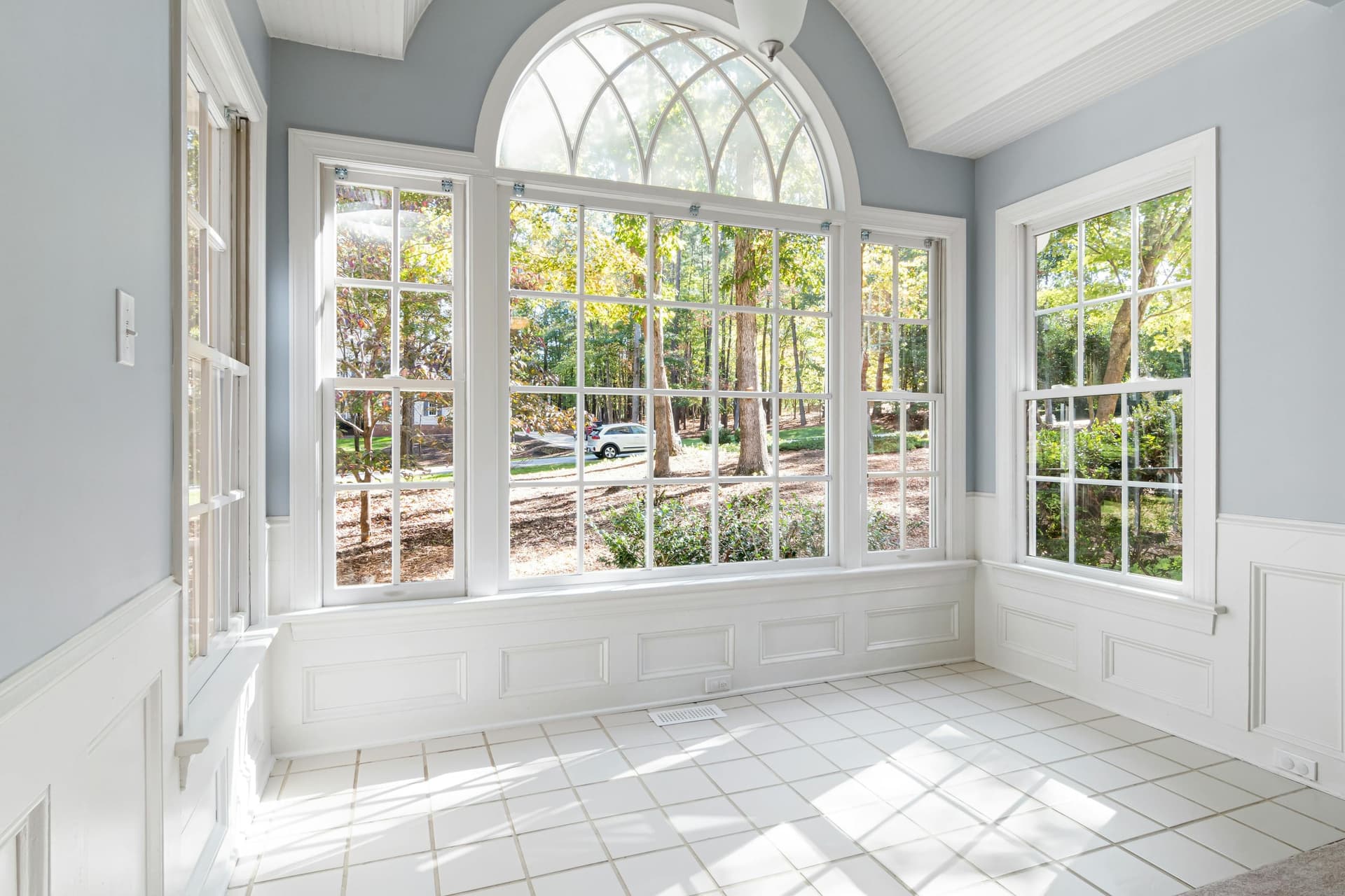 Sunroom addition with an arched window wall and painted wainscoting