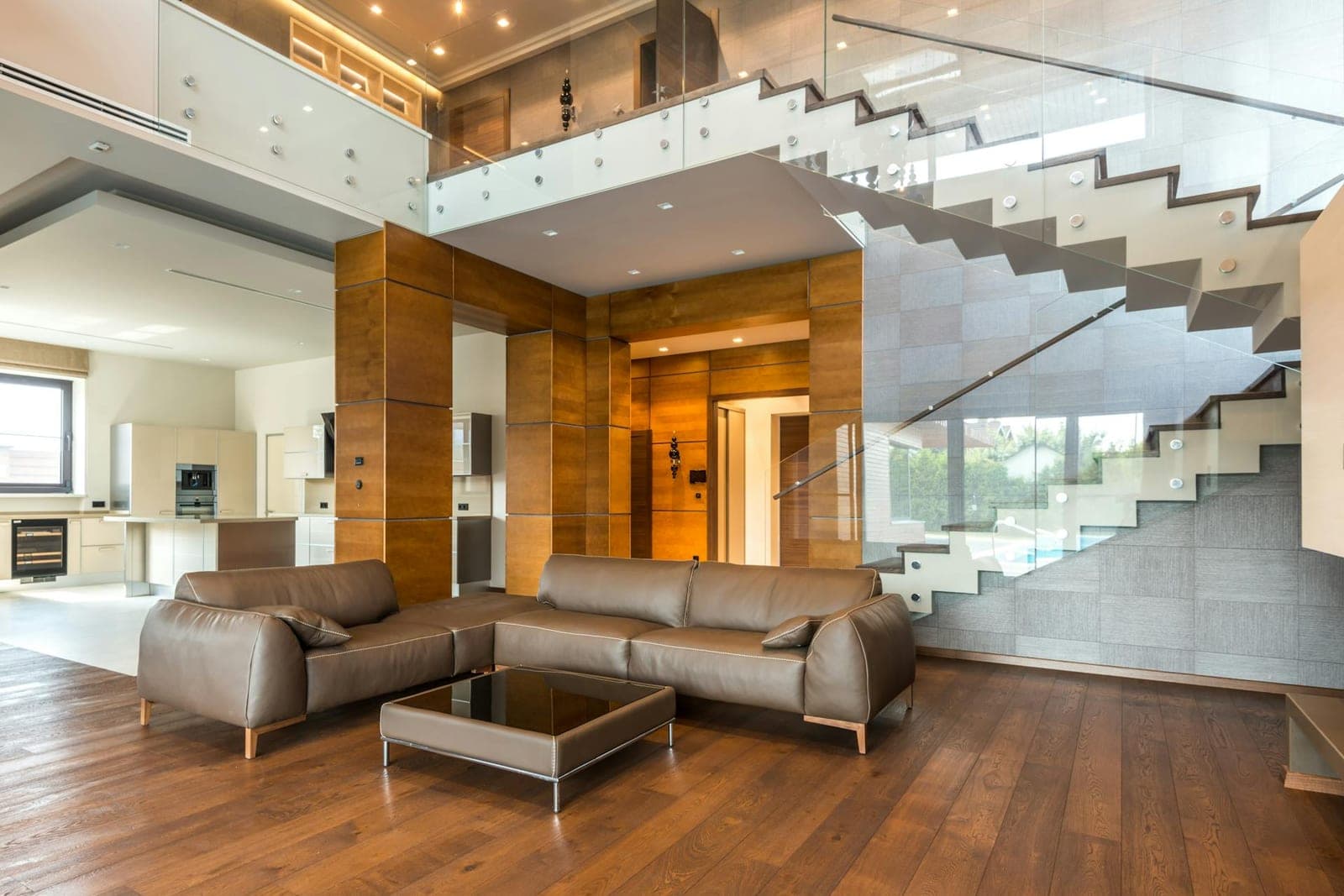 Open-plan living space with wide-plank floors and a glass-rail staircase