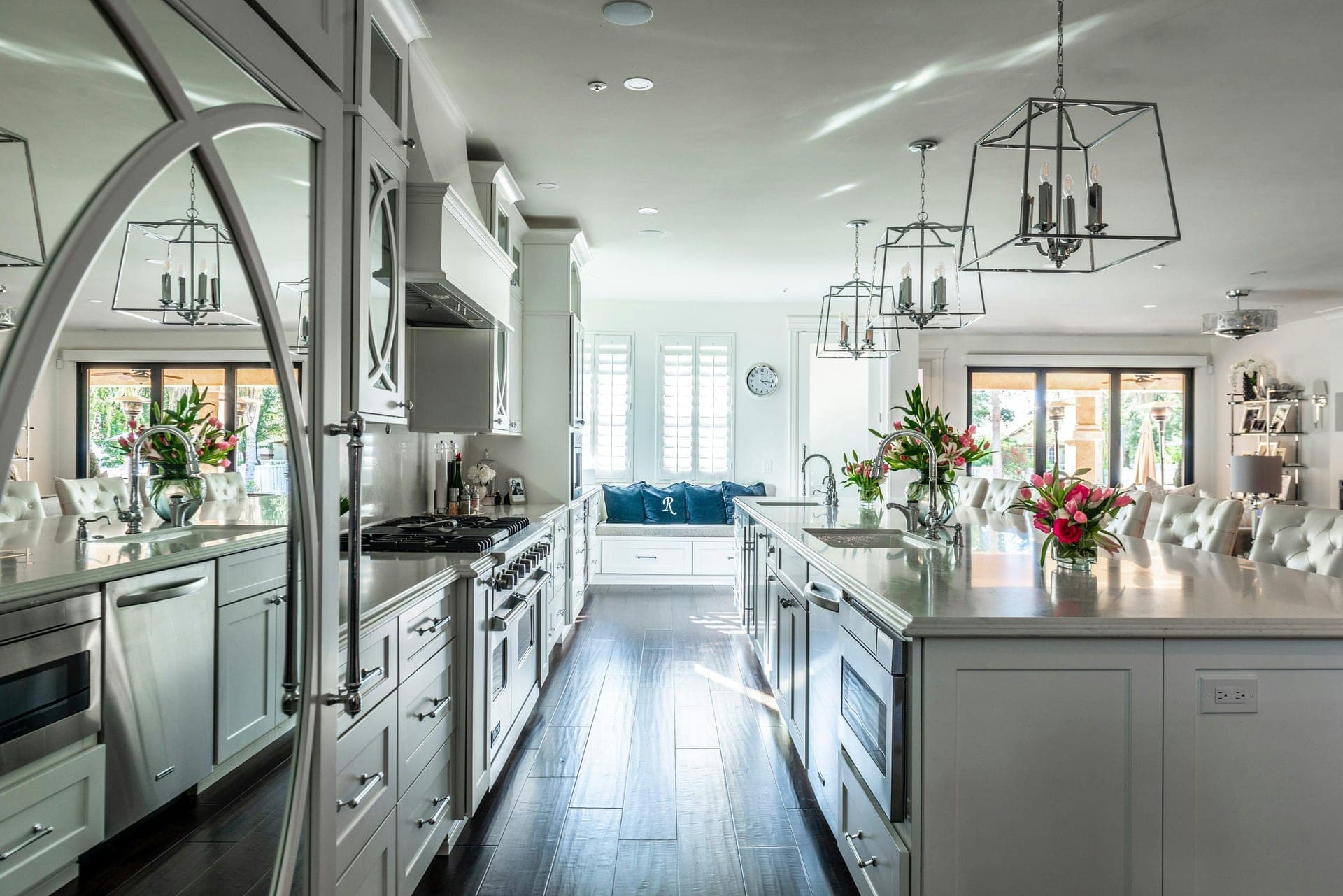 White kitchen with a long island, lantern pendants and dark hardwood floors