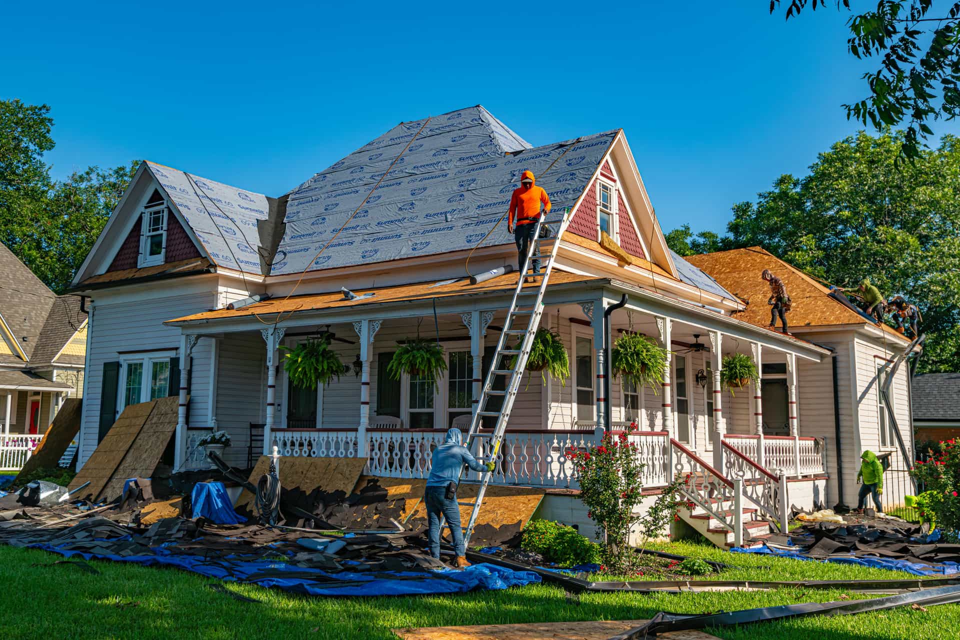 Crew re-roofing a Victorian home with porch and dormers