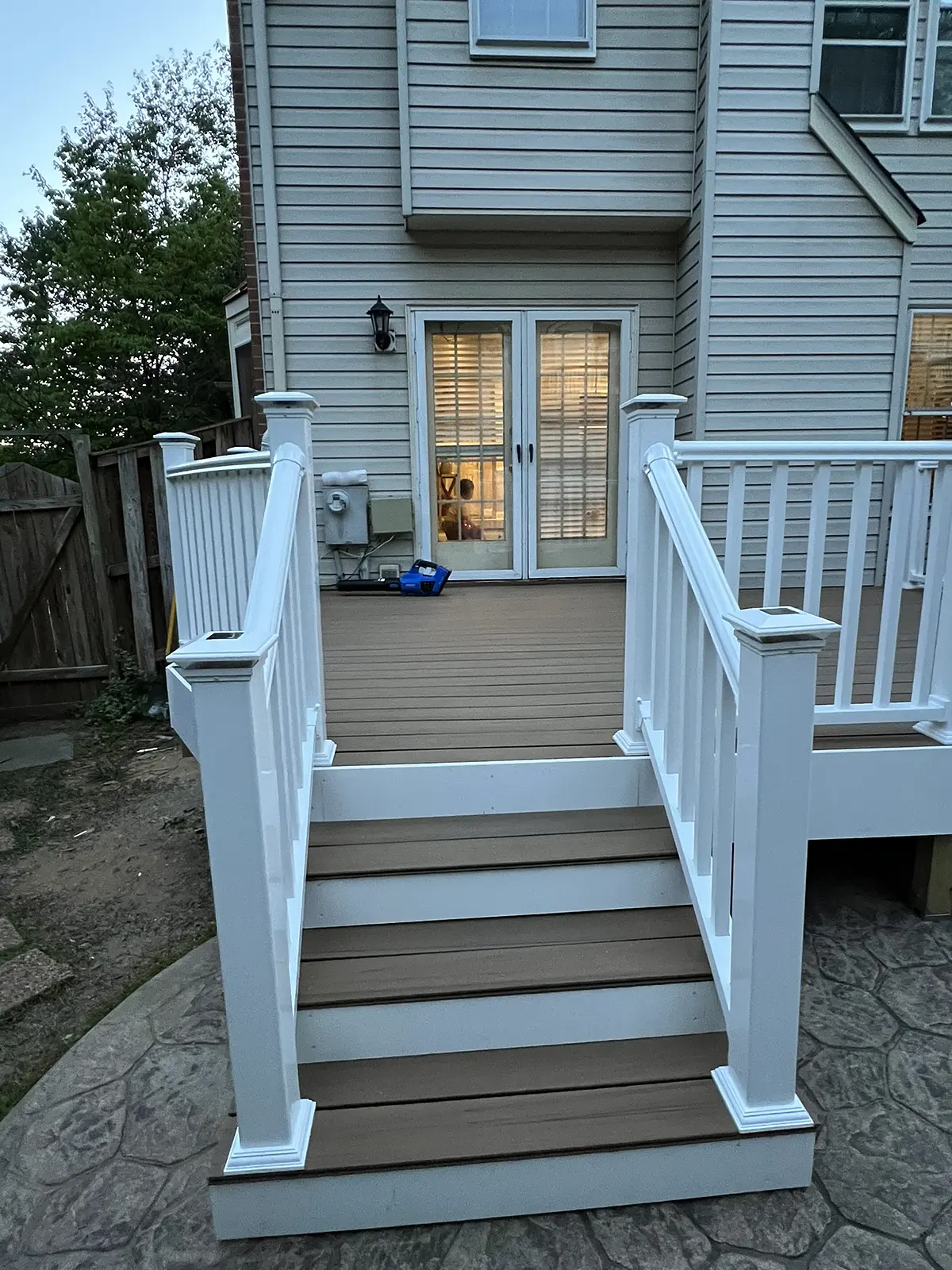 Composite deck with white vinyl railings and a wide stair down to the patio