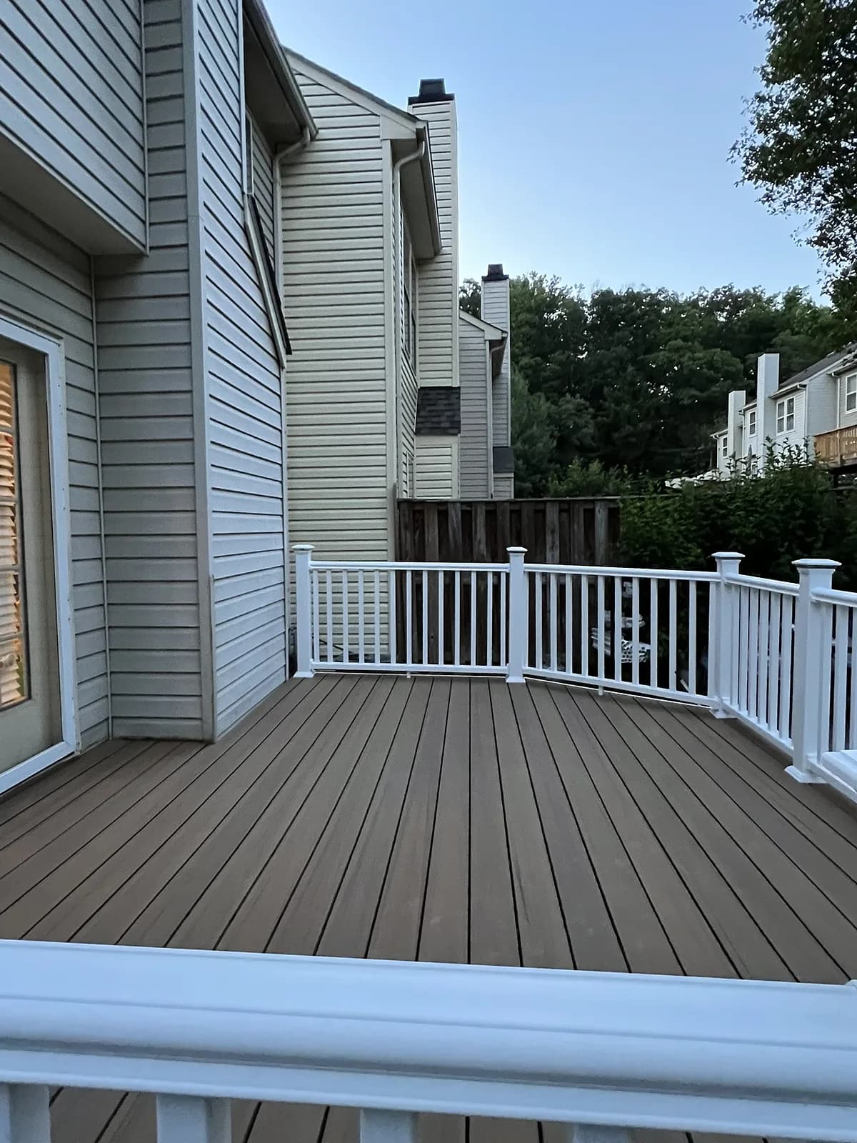 Brown composite decking with a curved run of white vinyl railing