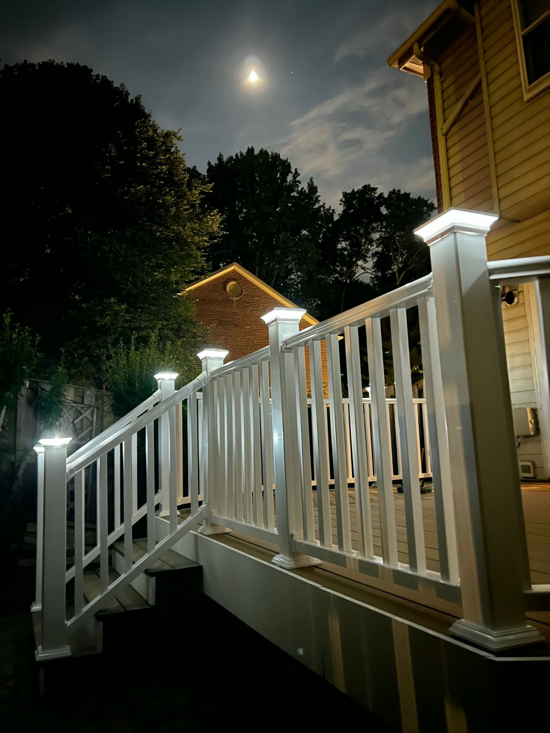 Deck railing at night with the moon above